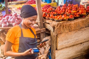 Woman selling fruits in a market using mobile payment 