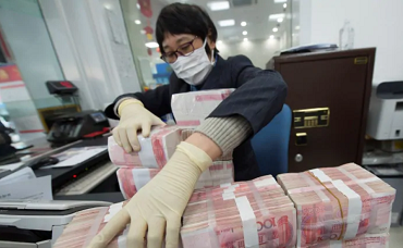 A bank employee wearing a mask arranges stacks of Chinese yuan notes at a bank in Nantong, Jiangsu province, China on Jan 30, 2020.PHOTO: REUTERS
