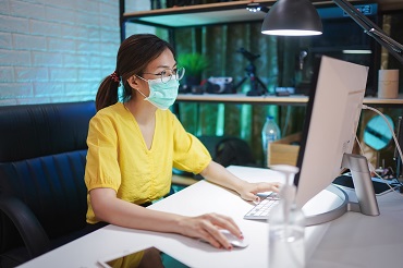 Woman with mask on a computer working
