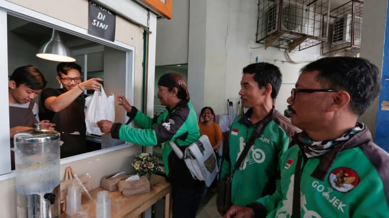 Go-Jek drivers wait for orders at a coffee stall in Jakarta- The app has become much more than a ride hailer -Credit Reuters