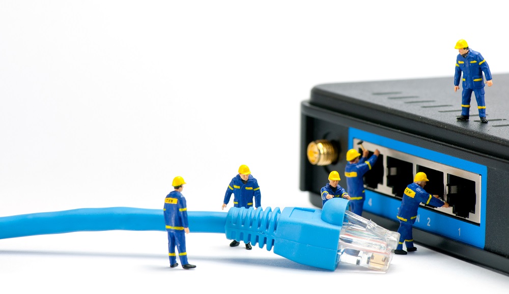 Back of a modem with small worker figures connecting a big blue cable