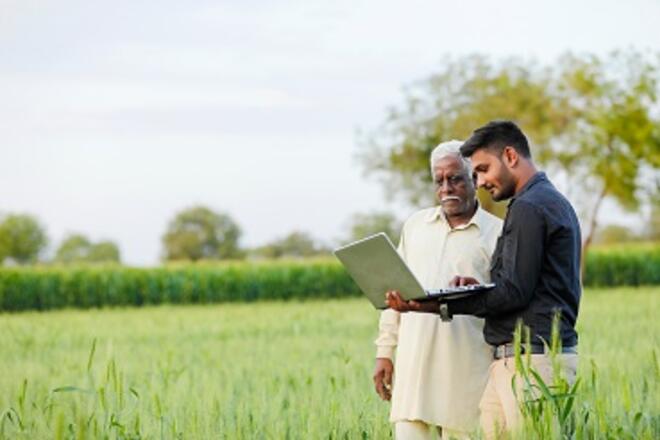 Old man and young man with computer on a crop field