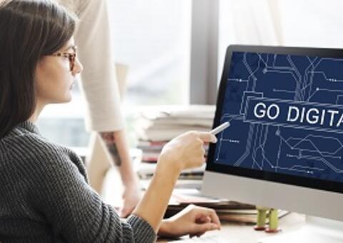 Woman in front of computer monitor point at the screen with legeng: Go Digital