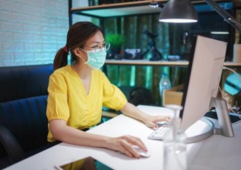 Woman with mask on a computer working