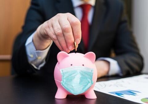 Man in suit inserting a coin on a piggy bank with mask